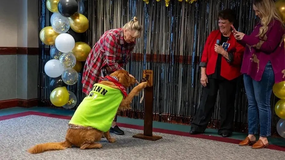 woman helping dog ring the bell