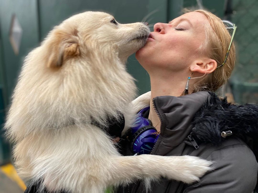 woman kissing white dog