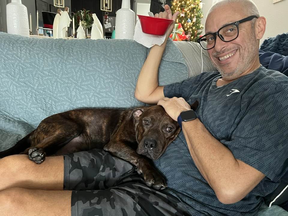 dog lying in man's lap on a couch