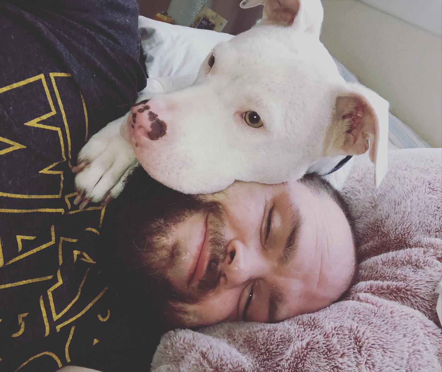 man cuddling with his dog on bed