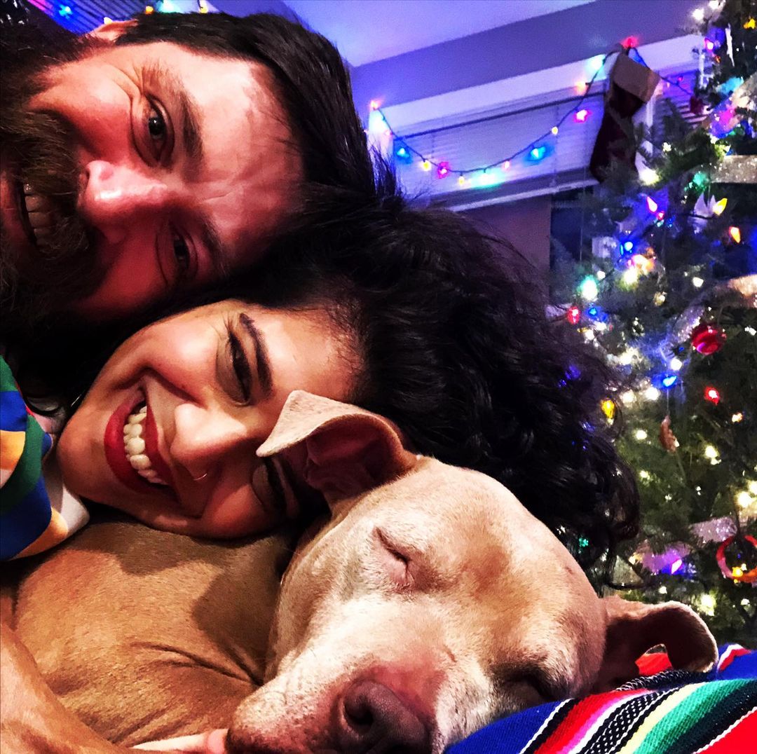 man, woman and pitbull lying in front of christmas tree