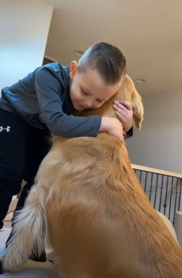 little boy hugging golden retriever