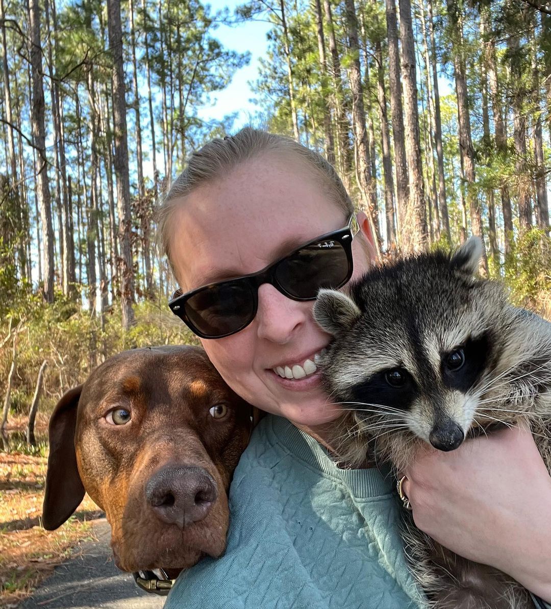 photo of woman, raccoon and a dog