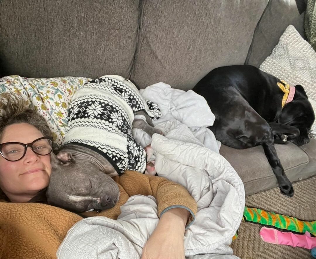 woman laying with two dogs