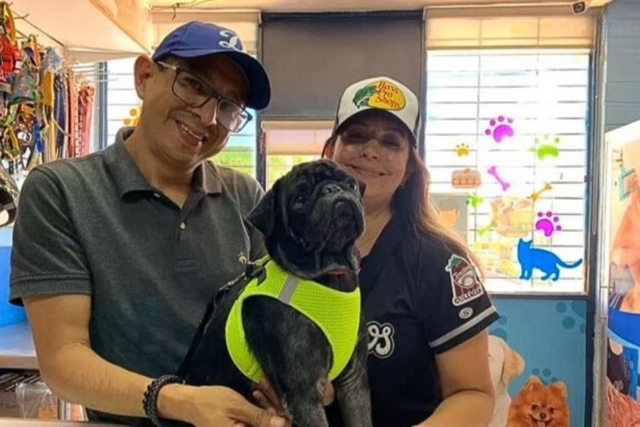 man and woman holding black dog