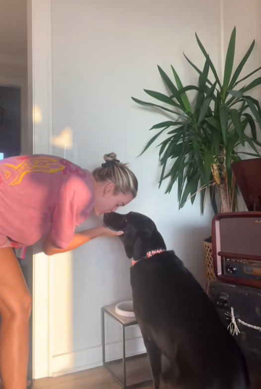 woman kissing a black dog
