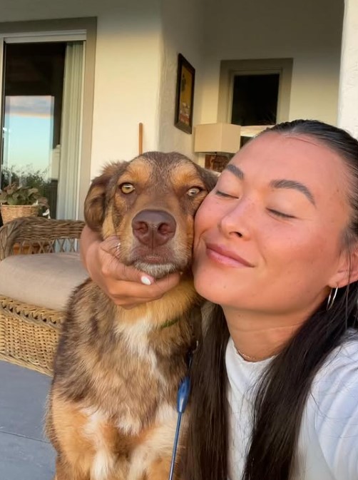 a girl takes a picture hugging a dog