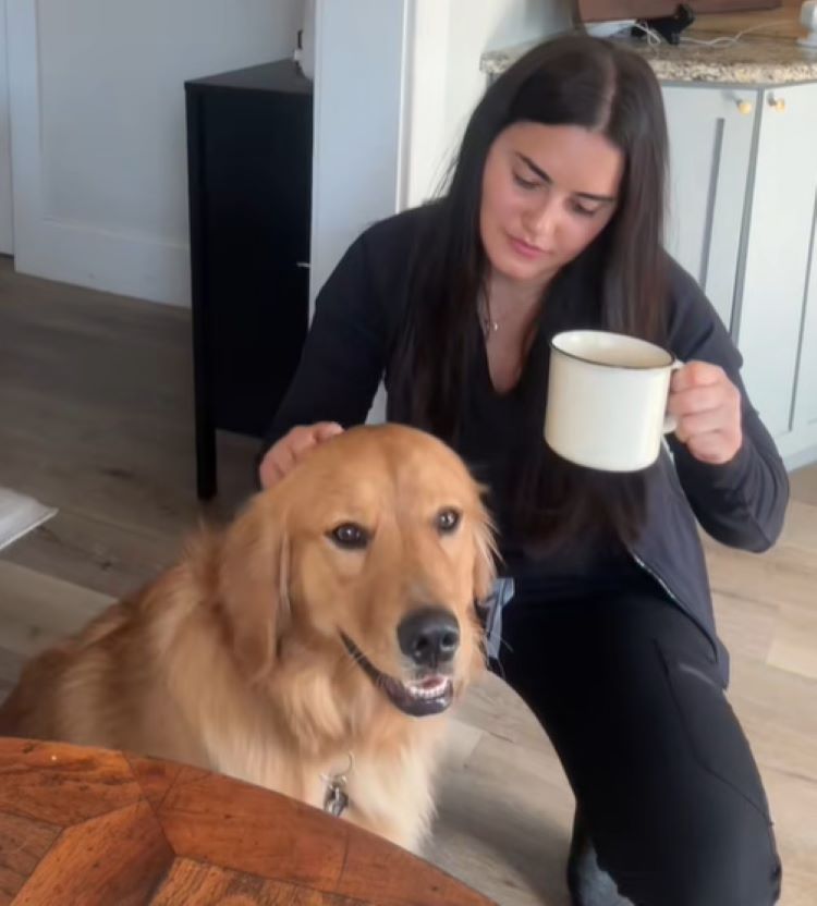 owner playing with dog and drinking a coffee
