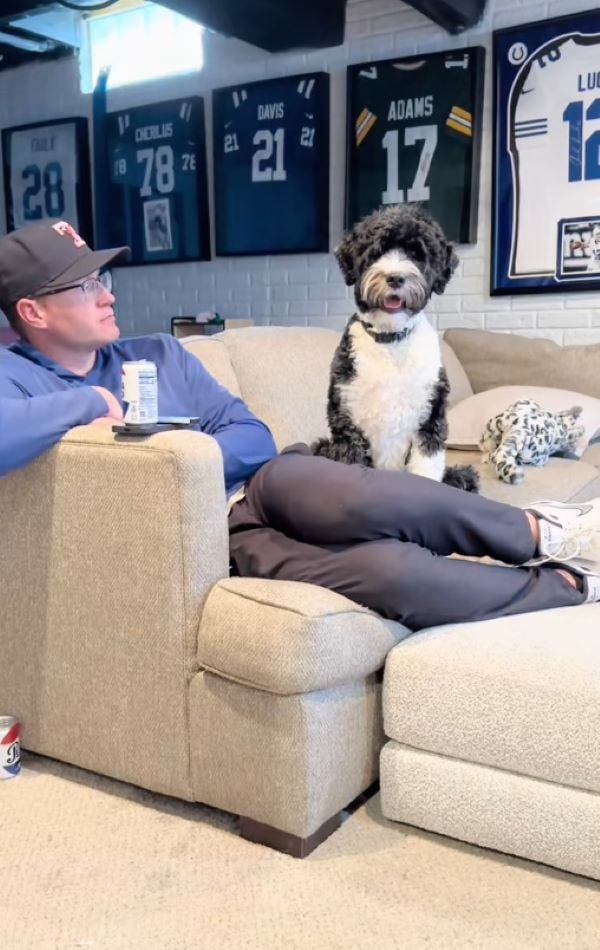 man and dog sitting on couch