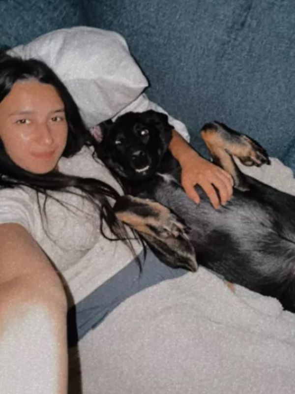 woman and black dog laying together