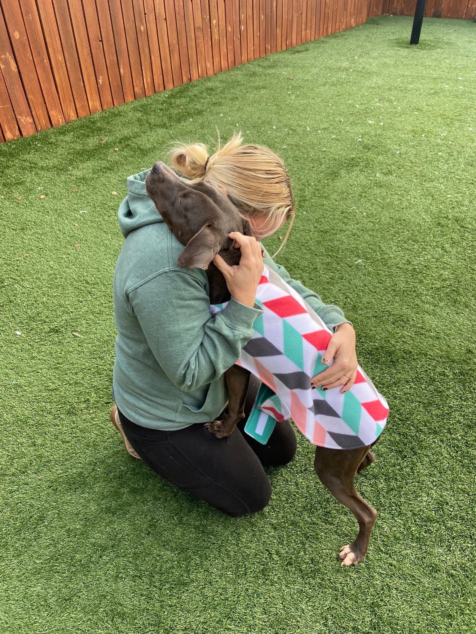blonde woman hugging a black dog