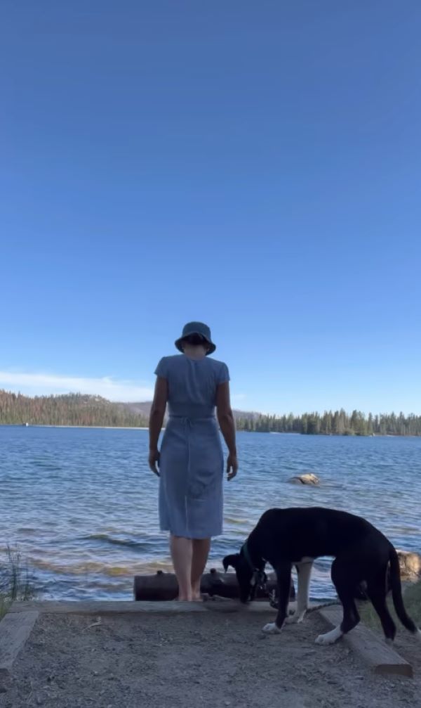 woman and black dog near lake