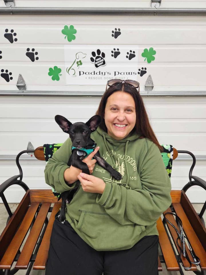 happy woman holding small black puppy