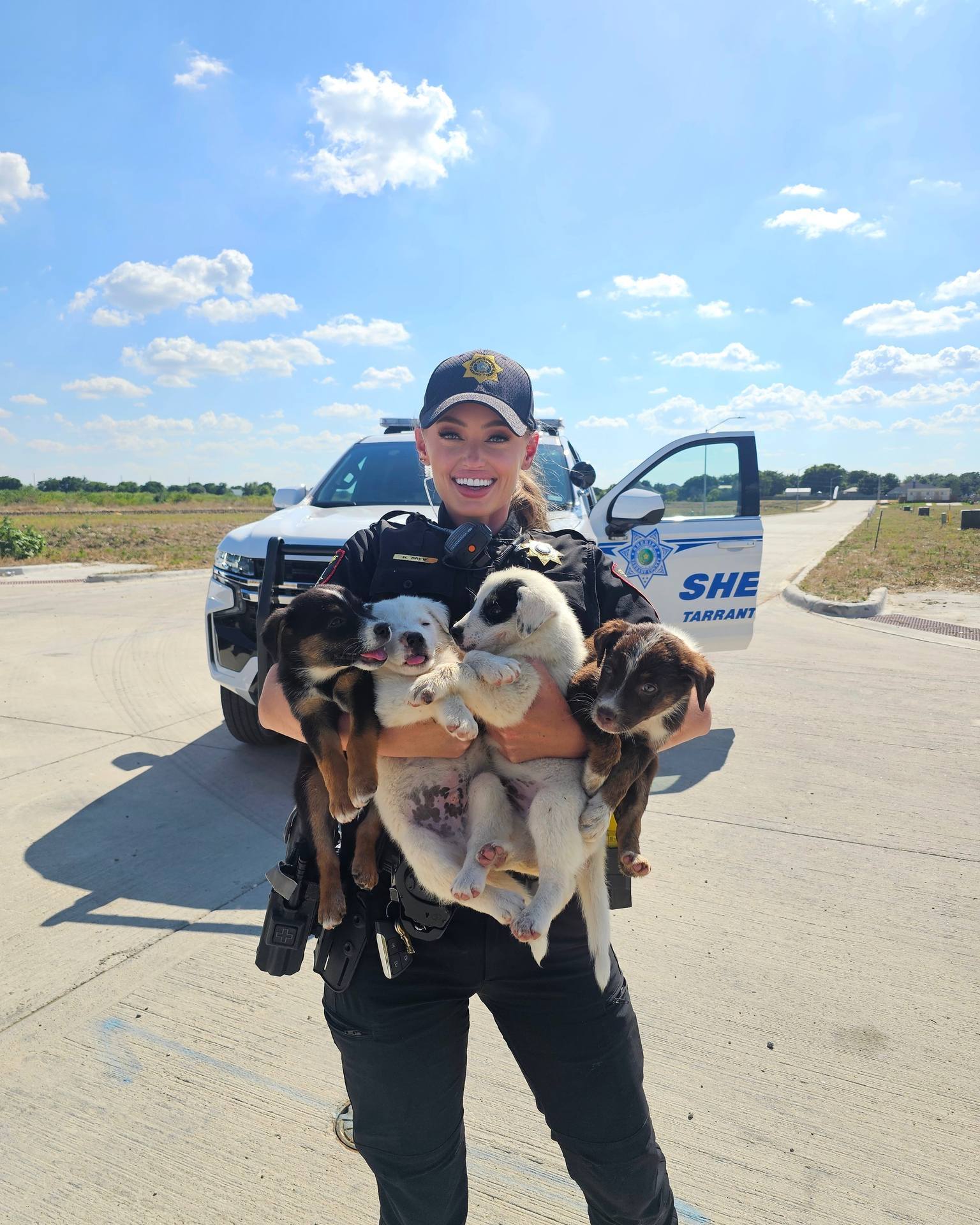 police officer holding four puppies