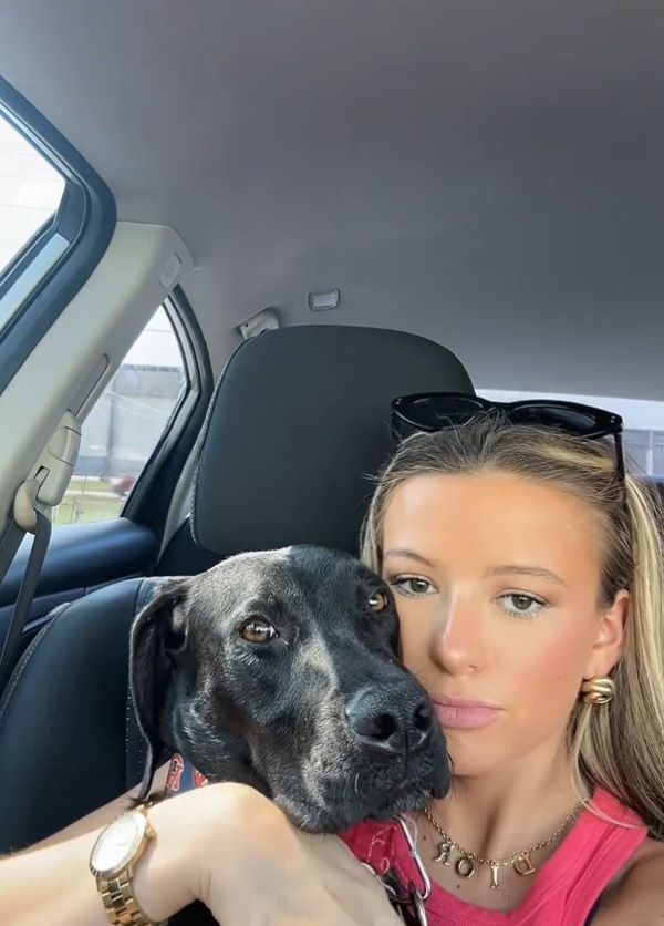 woman cuddling black dog 