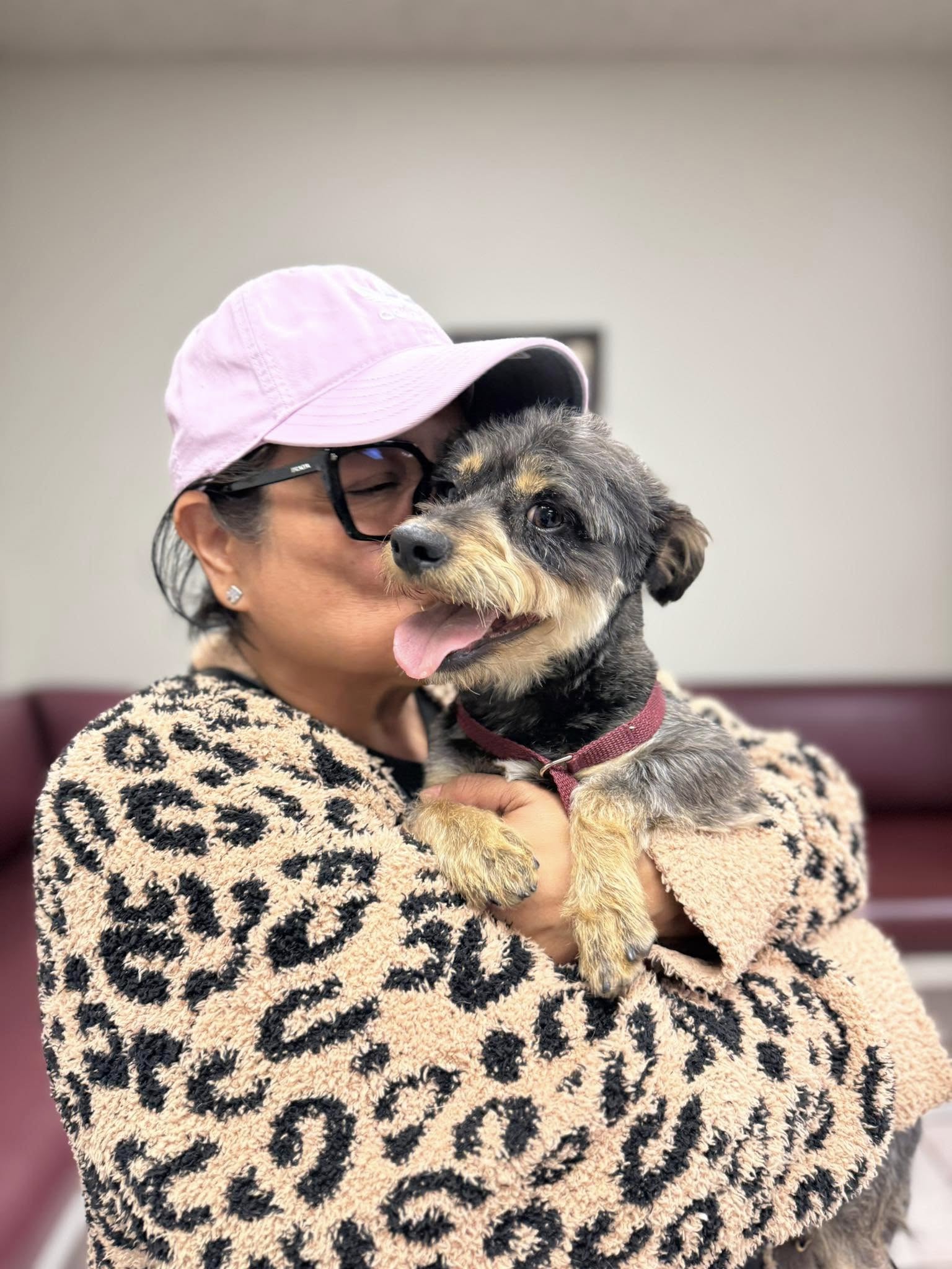 woman with pink hat kissing a little dog