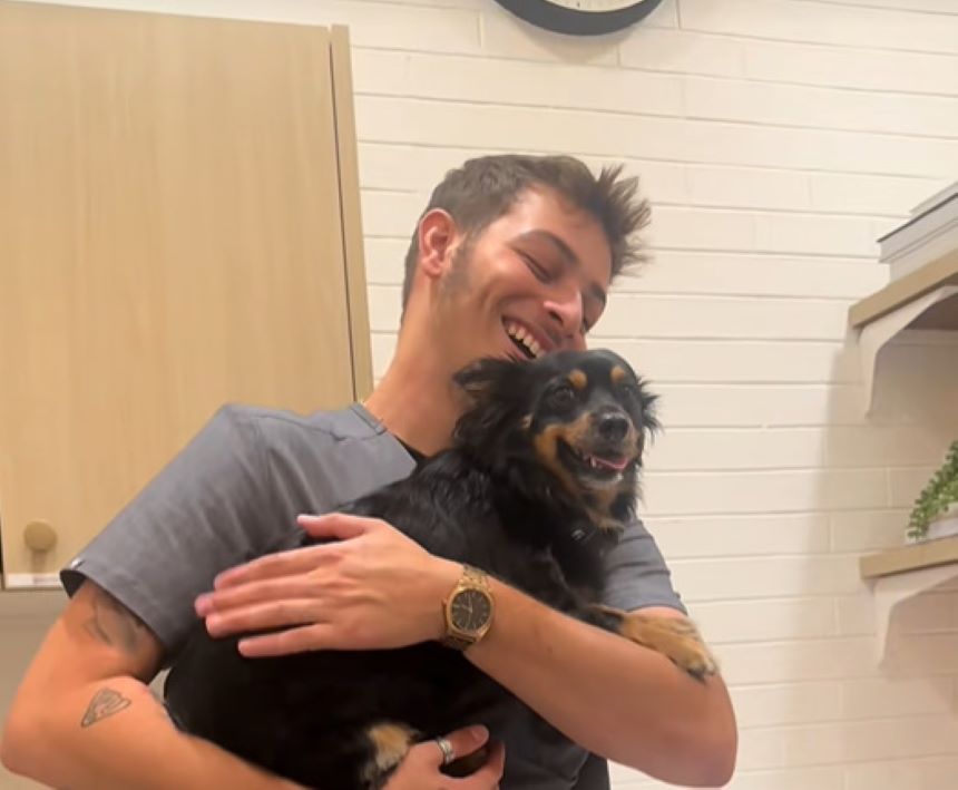 man holding a tiny black dog