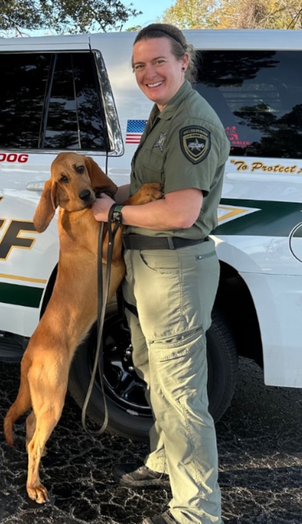 A policewoman takes a picture with a dog