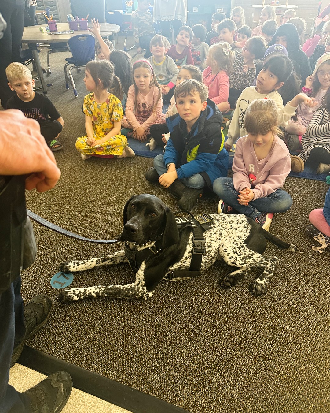 Police dog sitting in front of children