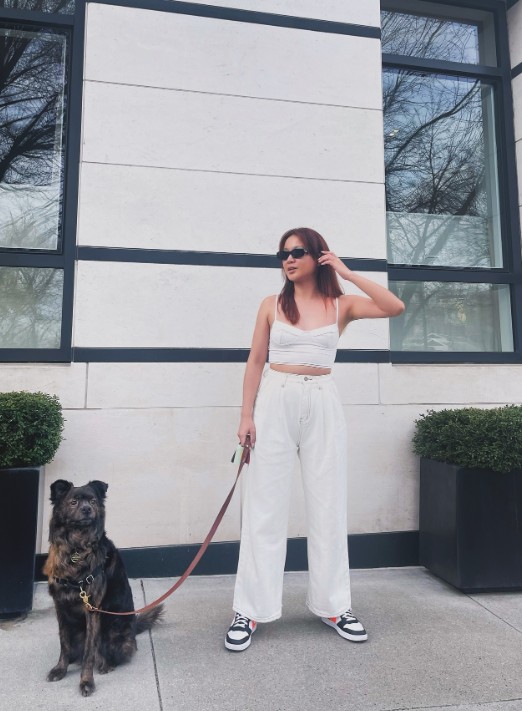 a girl stands with a dog on a leash