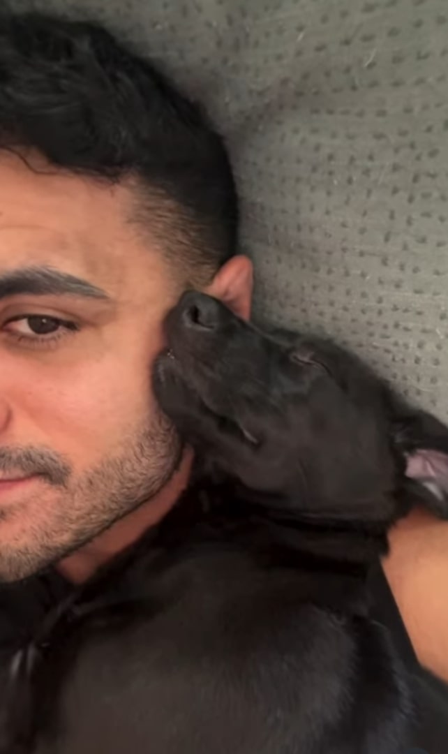 dog leaning against man's face sleeping
