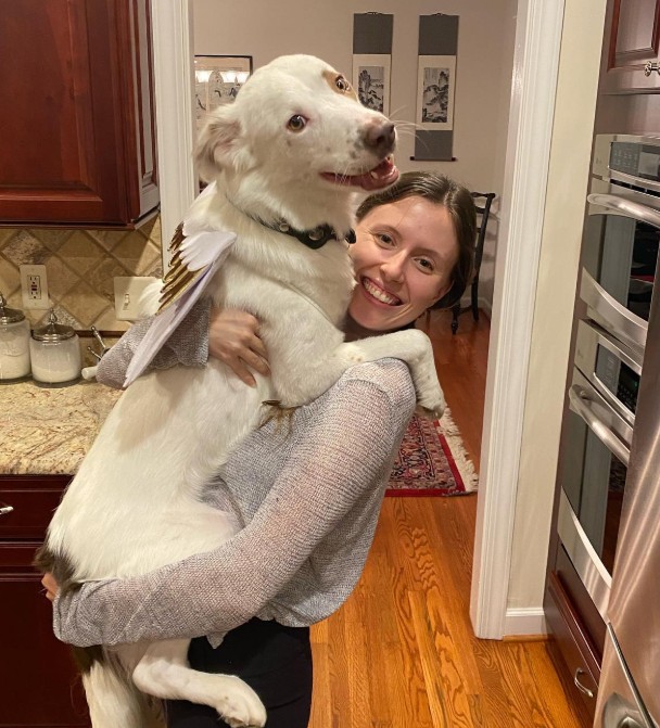 girl holding a white dog in her arms