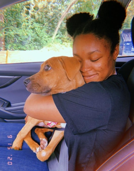 girl sitting in the car hugging a dog