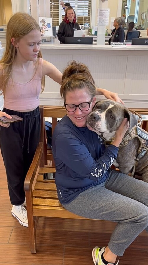 girl sitting on a chair hugging a dog