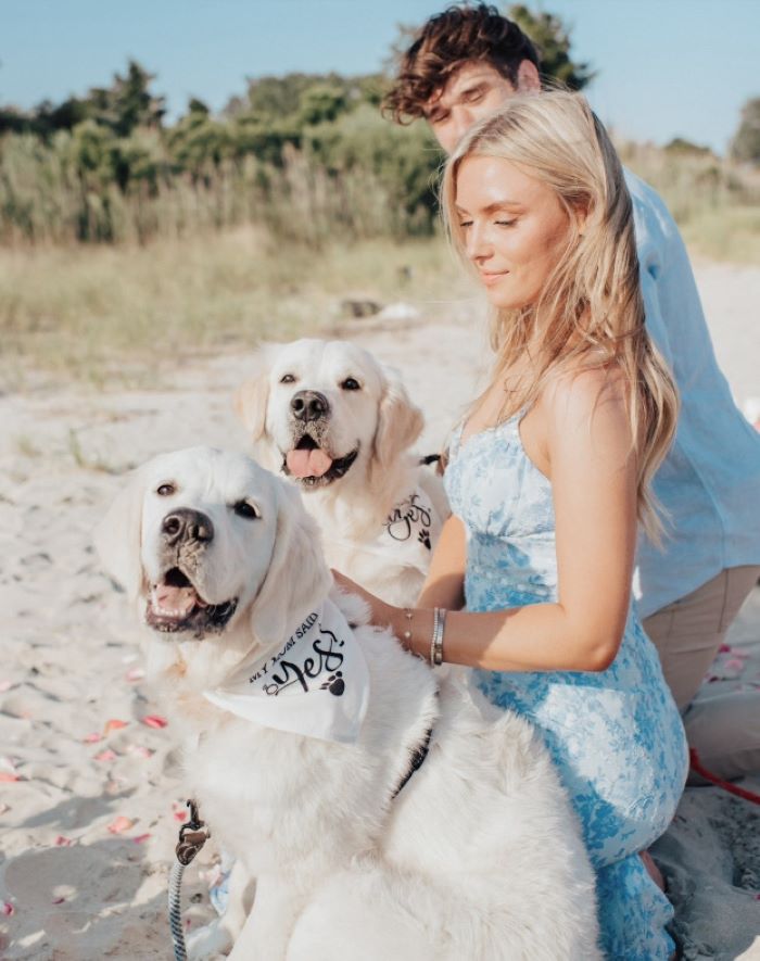 man and woman with two dogs on the beach