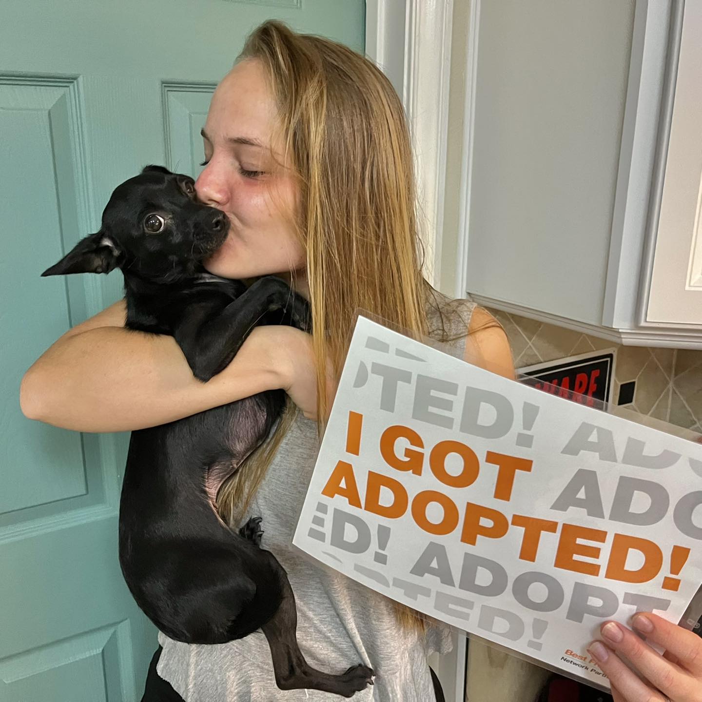 woman kissing an adopted puppy
