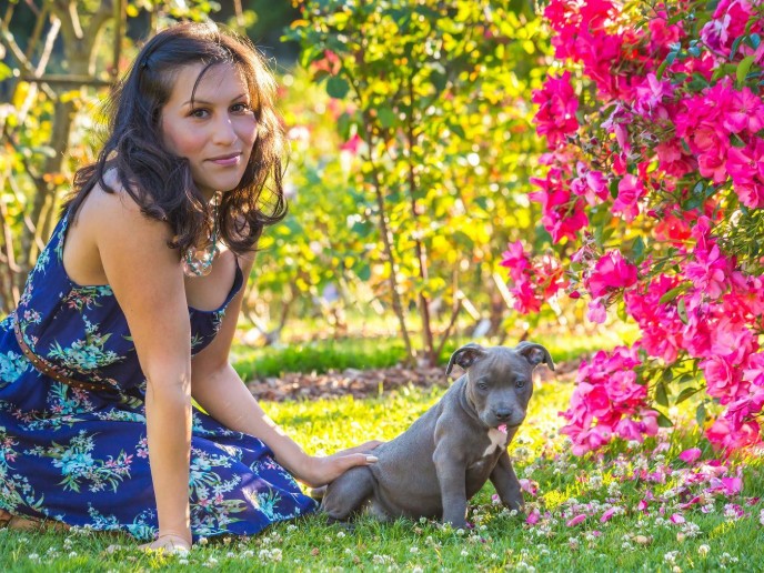 A dog and a woman are sitting on the grass