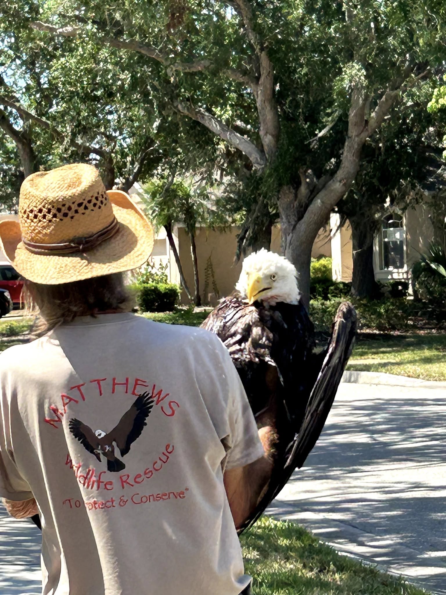 A man holds an eagle in his hand and walks down the street