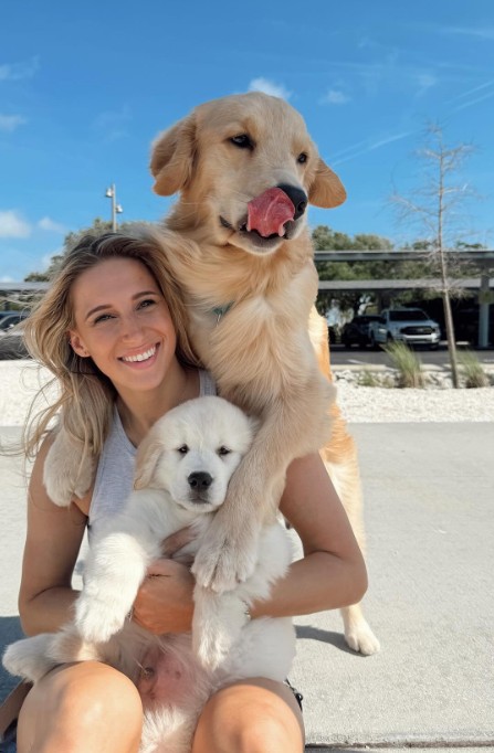 smiling girl sitting on the sidewalk with two dogs