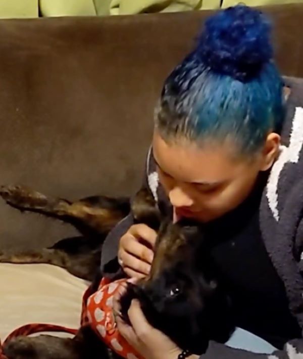 woman hugging a black dog