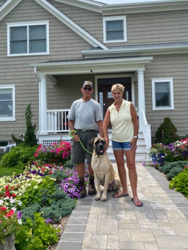 man and woman with dog in front of house