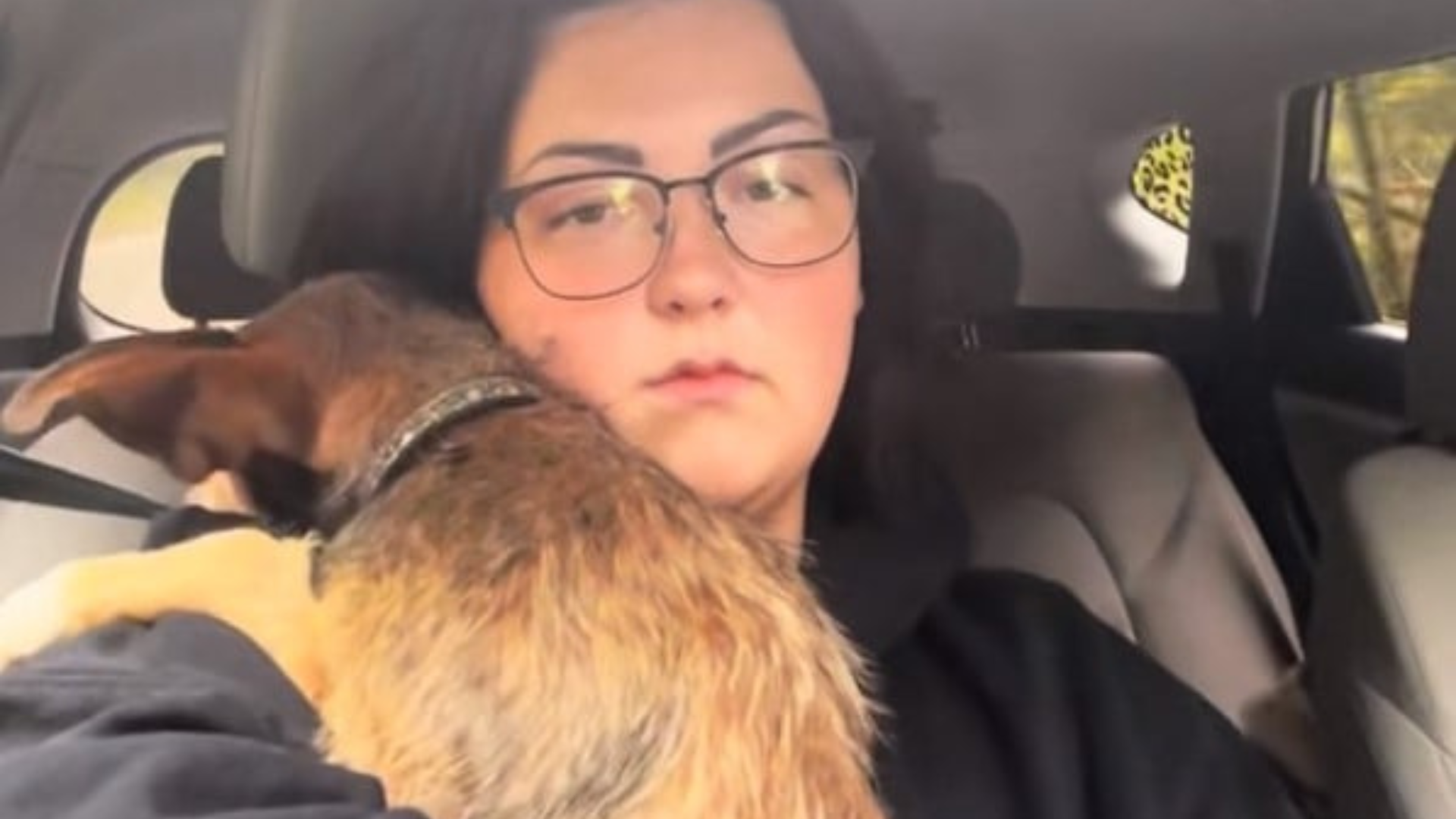 woman in car hugging dog
