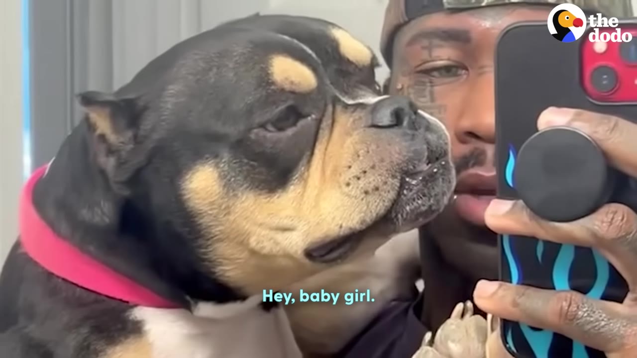 A close-up selfie of a man holding a black and tan dog close to his face.