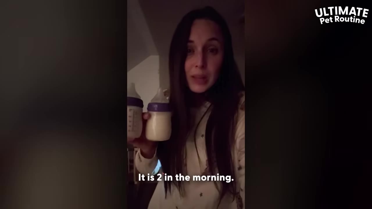 A woman with long dark hair stands in a dimly lit room at night, holding two baby bottles filled with milk, with the text 'It is 2 in the morning.' on the screen.