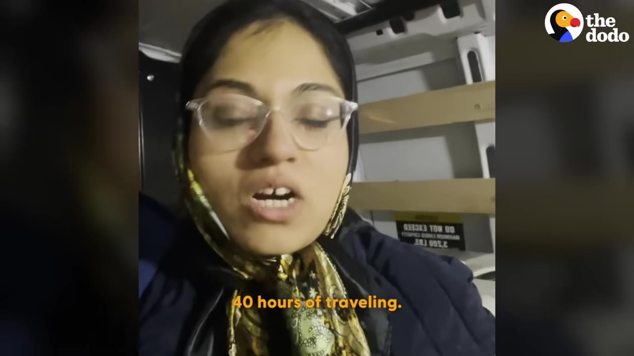 A close-up of a woman wearing glasses and a patterned headscarf speaking inside a vehicle, with the subtitle '40 hours of traveling' displayed at the bottom.