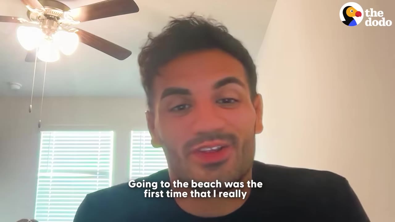 A man speaking to the camera with a ceiling fan in the background and subtitles that read, 'Going to the beach was the first time that I really'.