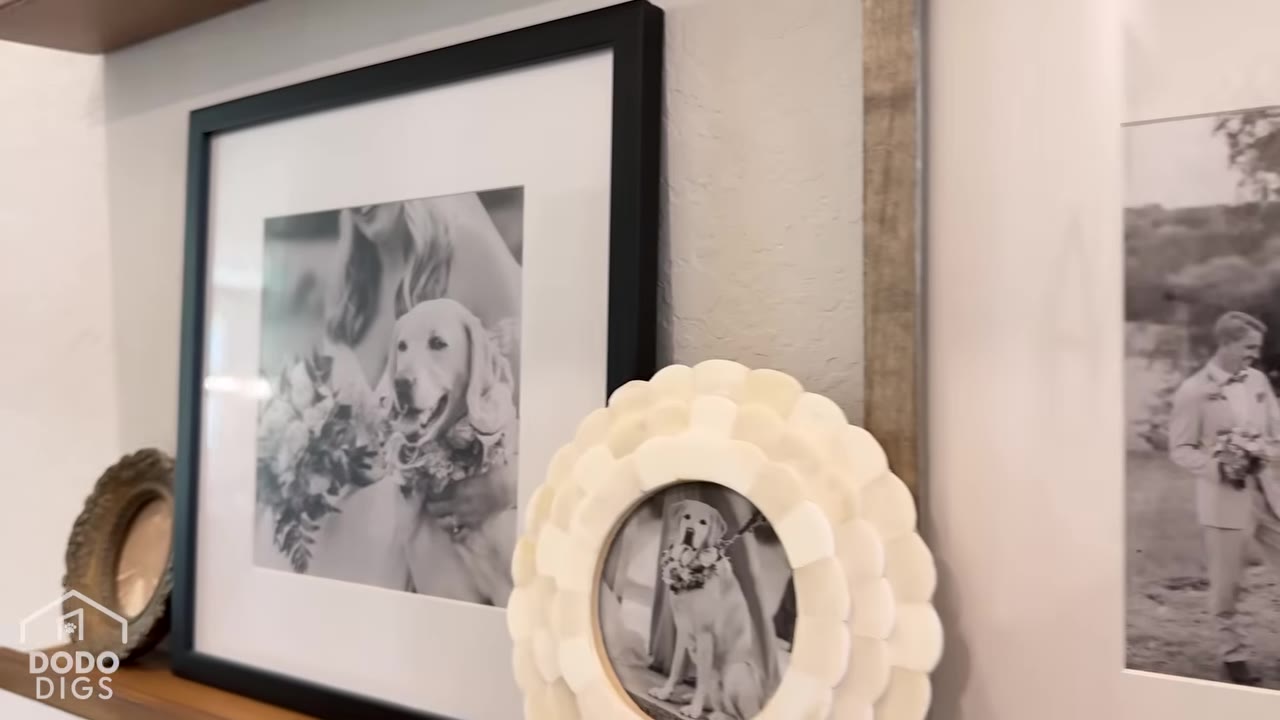A close-up of framed black-and-white photos on a shelf, featuring a golden retriever wearing a flower collar next to a bride.