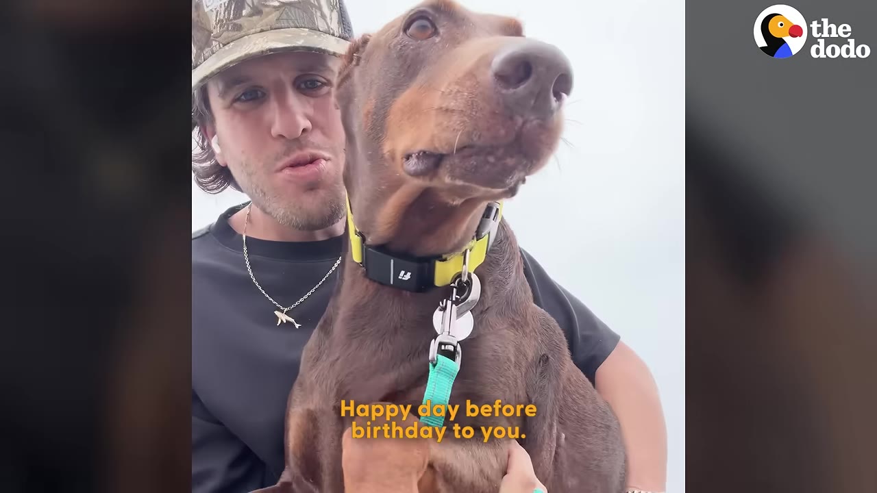 A man wearing a camouflage cap holds a brown Doberman close to his face as they celebrate together.