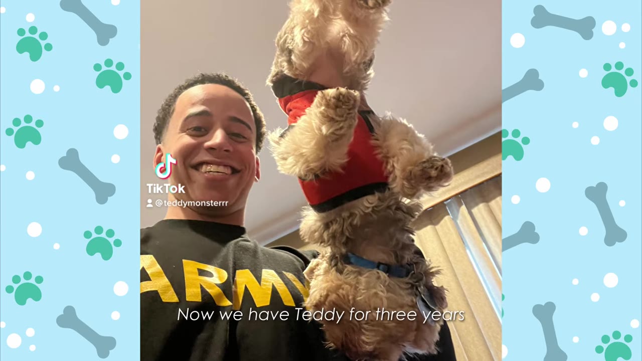 A smiling man wearing a black shirt with "ARMY" printed on it holds up a small Yorkshire Terrier wearing a red shirt.